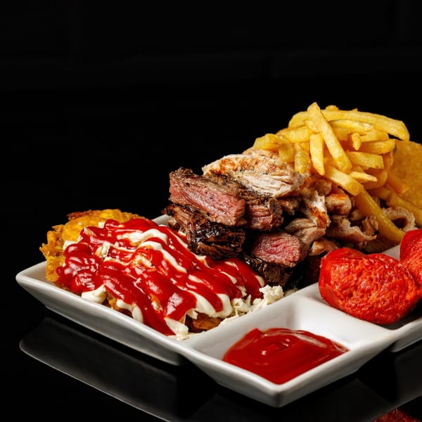 Pika's Ecuadorian platter with steak, chicken, fries, plantains with sauces, and red sausage.