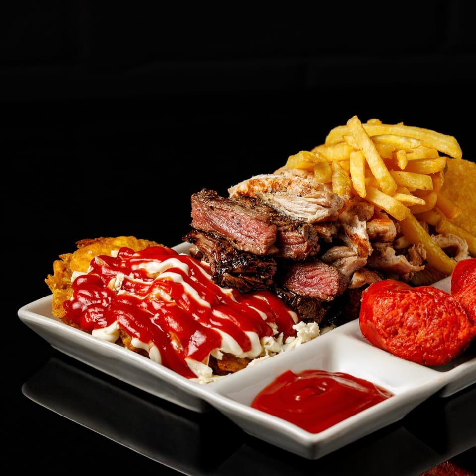 Pika's Ecuadorian platter with steak, chicken, fries, plantains with sauces, and red sausage.