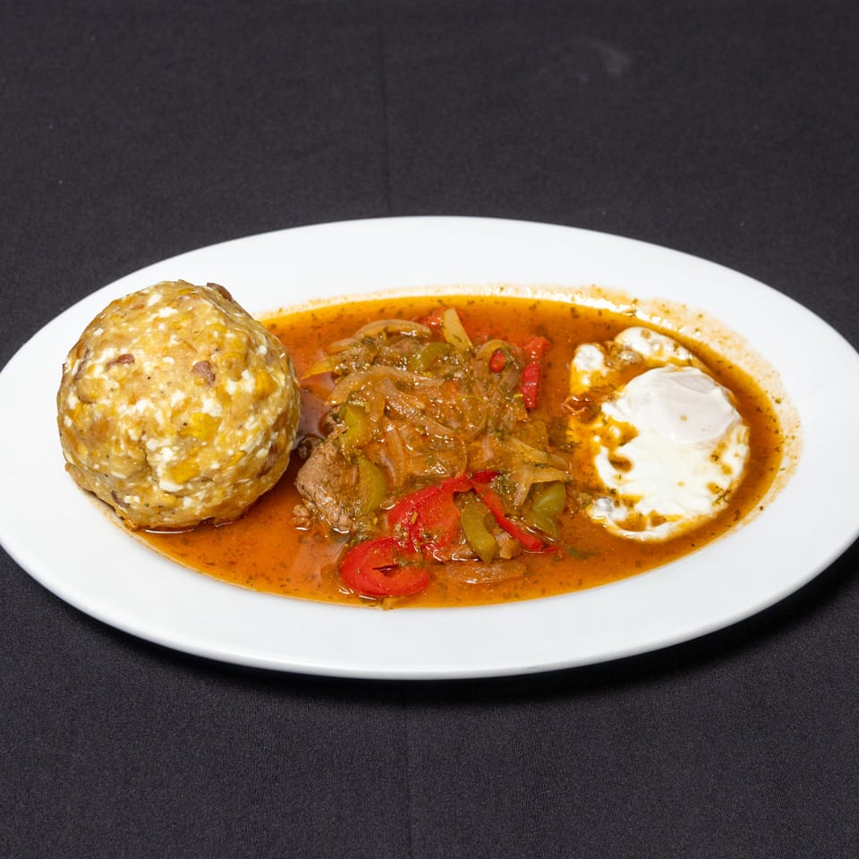 Ecuadorian dish with a plantain dumpling, meat stew with peppers and onions, and a fried egg.