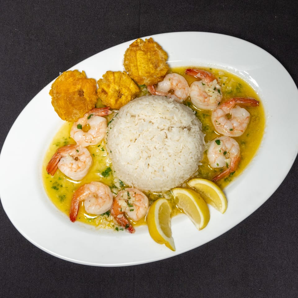 Pika's Restaurant's Ecuadorian shrimp dish with rice, fried plantains, and lemon wedges.